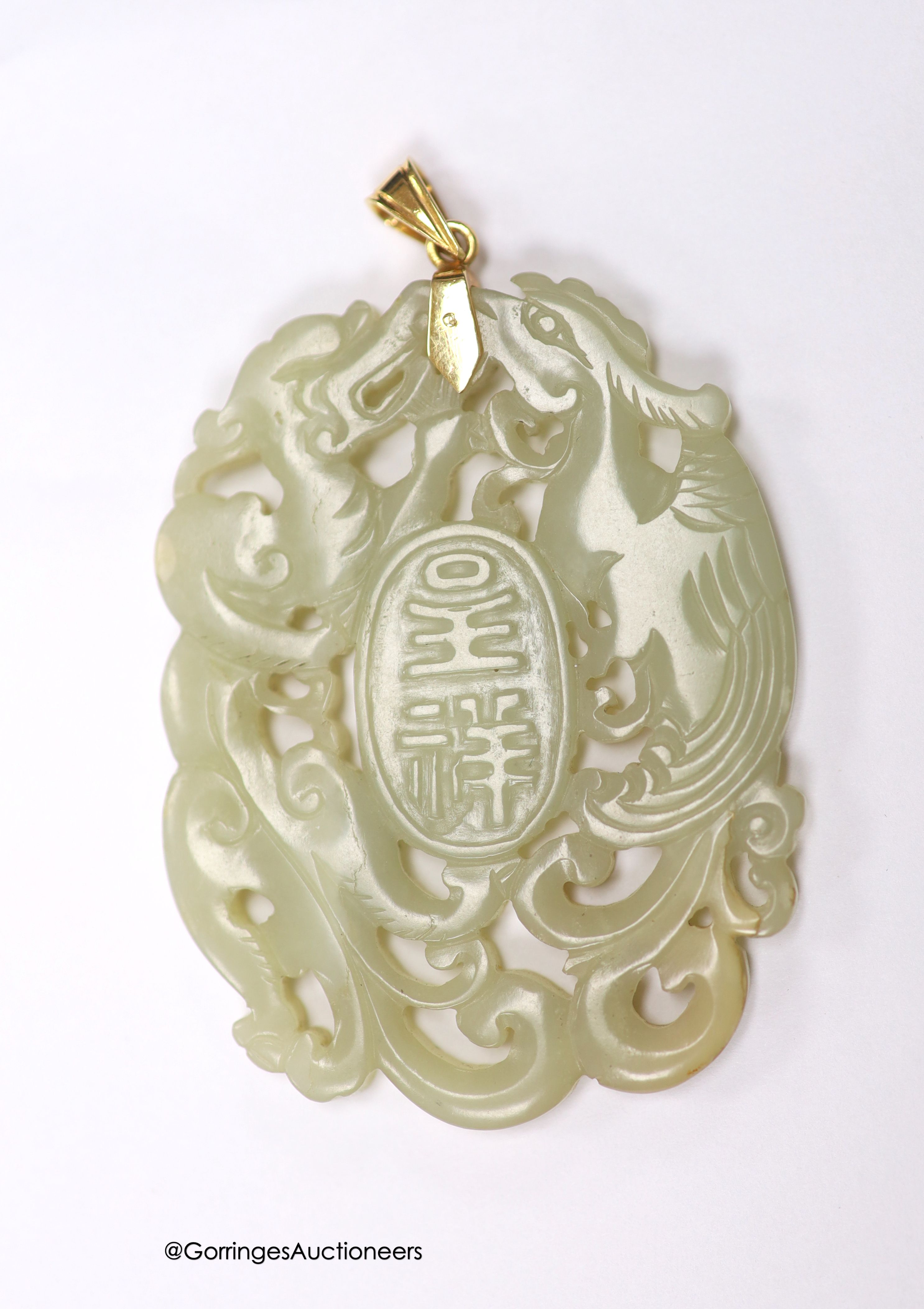 A Chinese yellow metal amounted jade pendant, 63mm, carved with dragons and character marks.